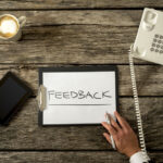 A clipboard is sitting on a desk with customer feedback written on it after a phone survey was conducted.