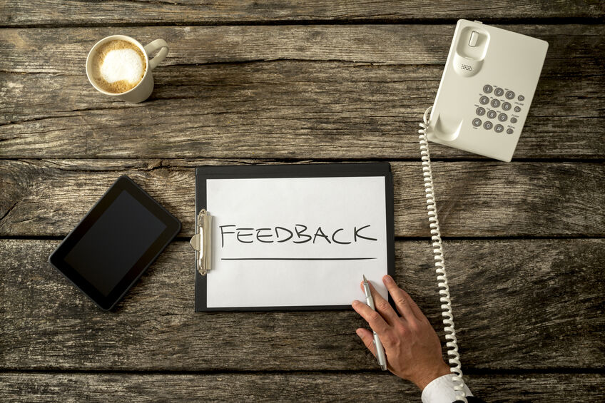 A clipboard is sitting on a desk with customer feedback written on it after a phone survey was conducted.