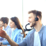 Portrait of call center worker accompanied by his team. Smiling customer support operator at work